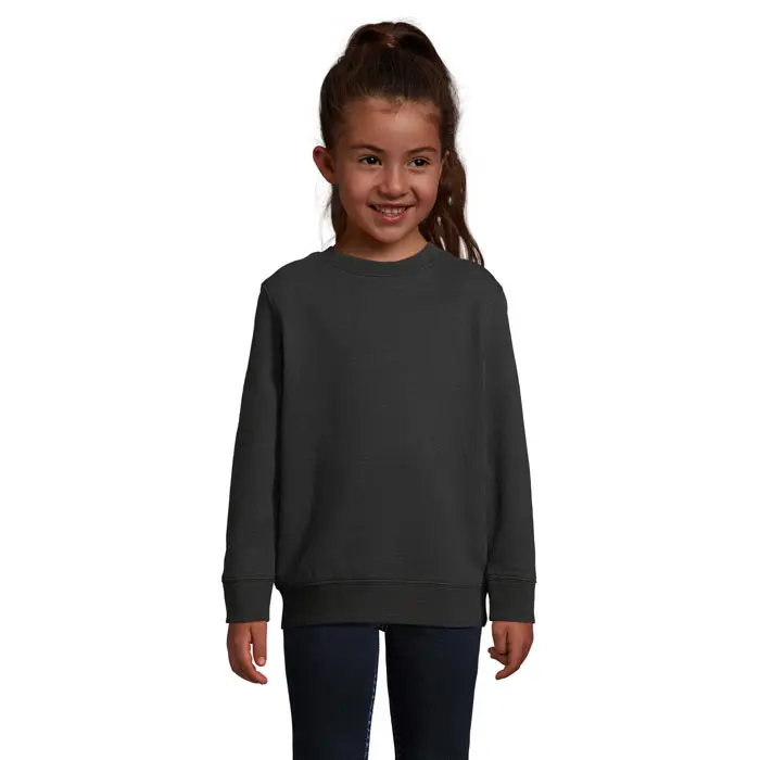 Niña con sudadera básica gris oscuro de algodón y pantalones oscuros.