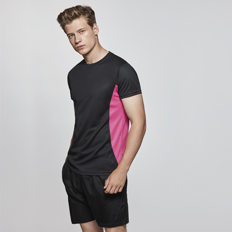 Hombre con camiseta deportiva negra con detalles rosa y pantalones cortos negros.