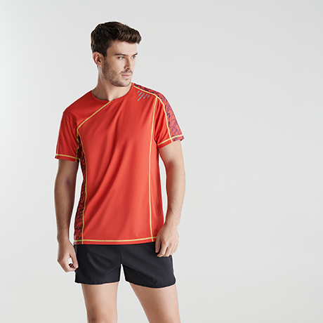 Hombre con camiseta deportiva roja con detalles naranjas y pantalones cortos negros.