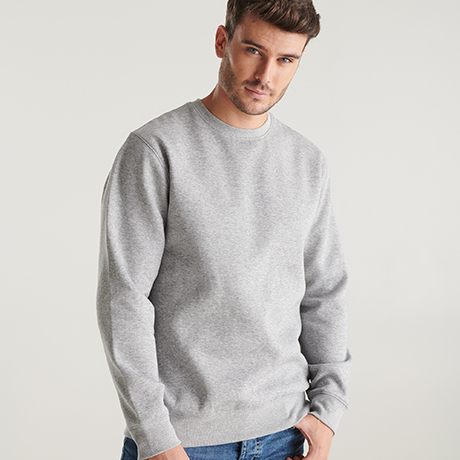 Hombre joven lleva una sudadera gris de manga larga y cuello redondo, combinada con vaqueros azules.