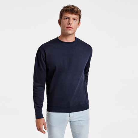 Hombre con sudadera azul marino de manga larga y cuello redondo combinada con pantalones vaqueros claros.