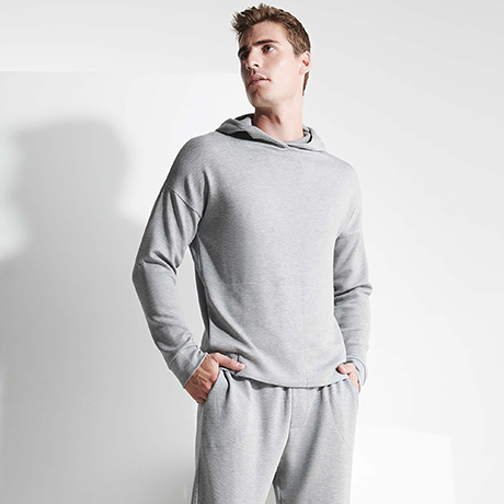 Hombre con chándal gris claro de algodón con capucha y pantalones a juego.