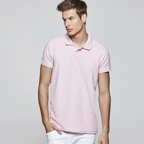 Hombre con polo rosa de manga corta y pantalón blanco.