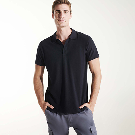 Hombre con camiseta polo negra de manga corta y pantalones grises con bolsillo lateral.
