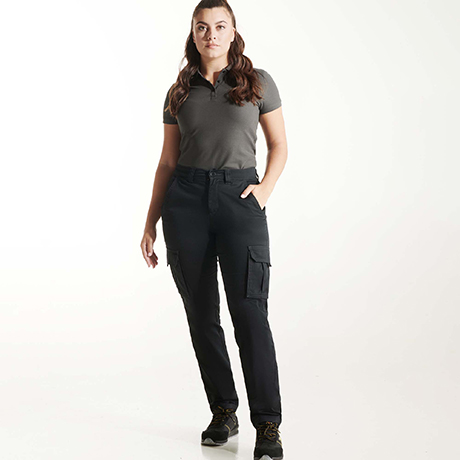 Mujer con camiseta polo gris y pantalones cargo negros con bolsillos laterales y zapatillas deportivas negras.