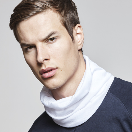 Hombre joven con cuello tubular blanco sobre camiseta azul marino.