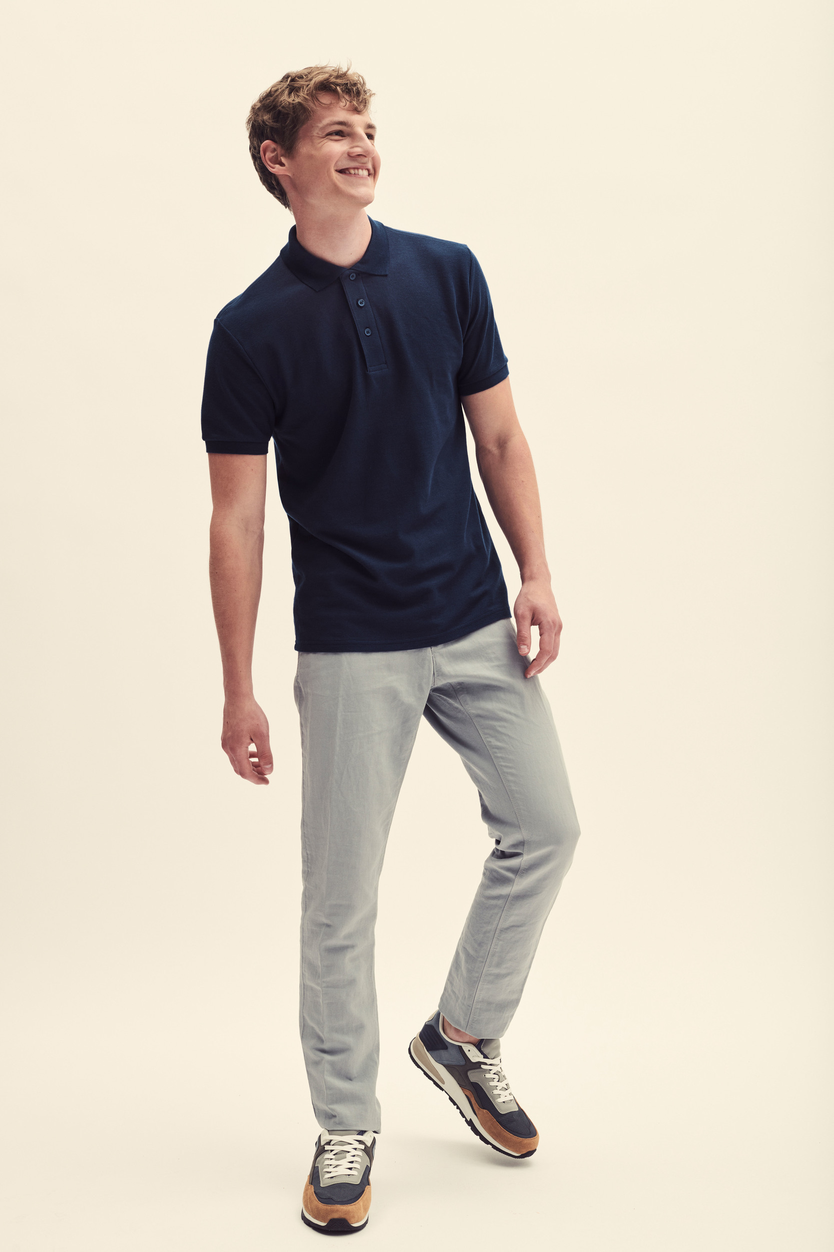 Hombre con polo azul marino de manga corta, pantalones grises y zapatillas deportivas multicolor.