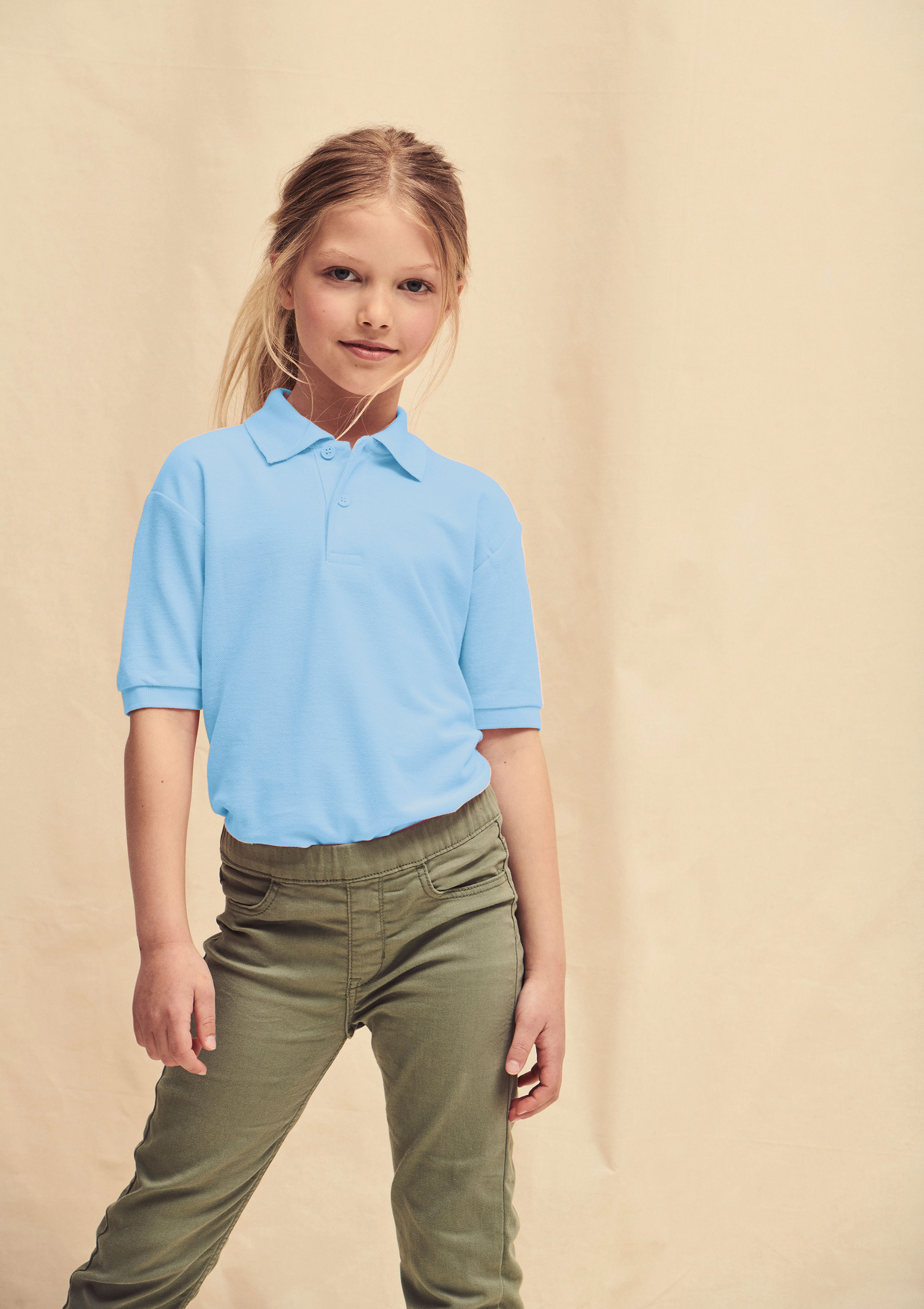 Niña con polo azul celeste de manga corta y pantalones verdes ajustados.