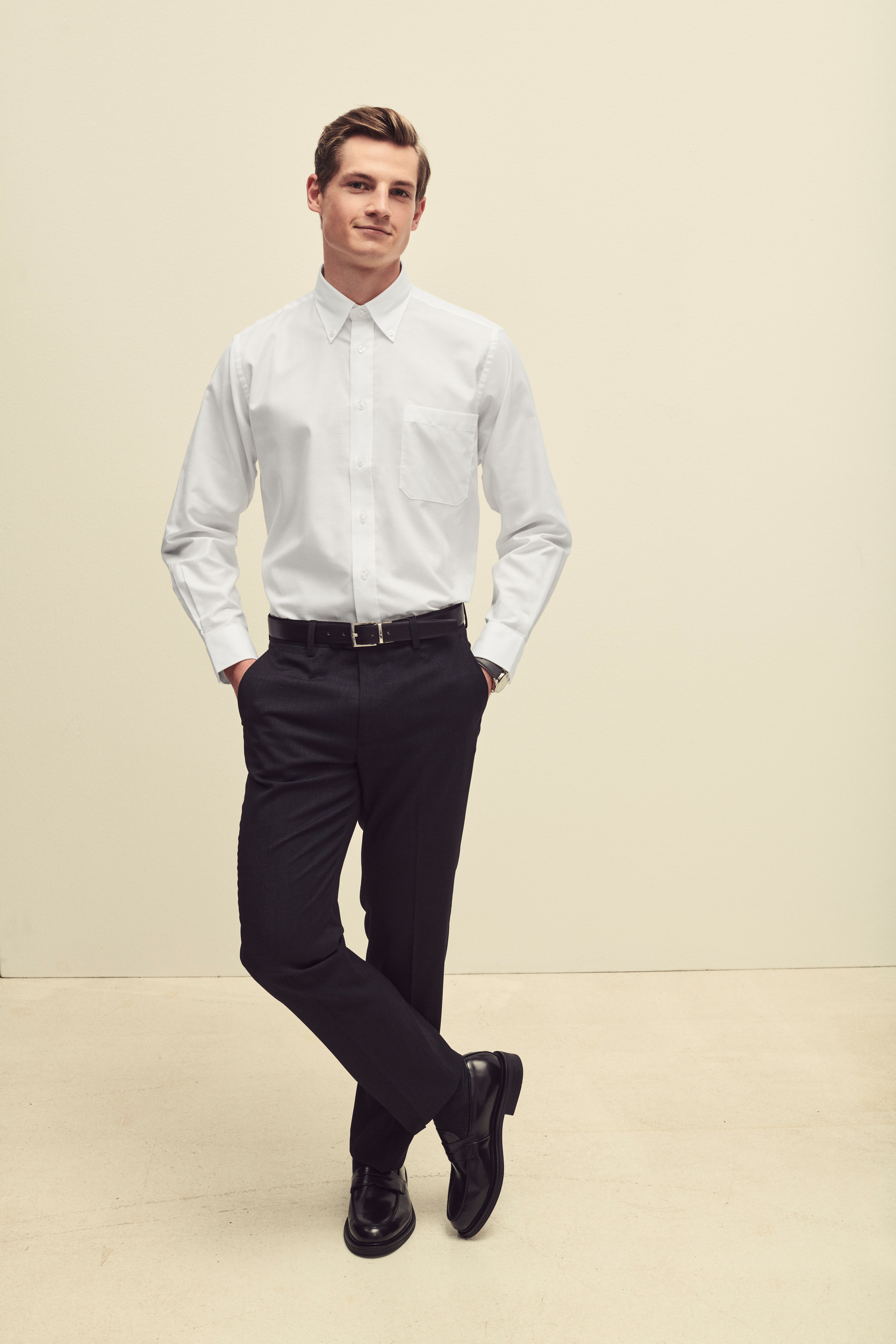 Hombre con camisa blanca de manga larga, pantalón negro y zapatos de cuero negros.